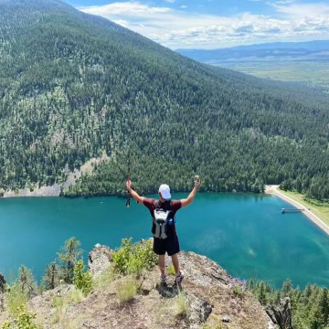 Joseph Lavalle standing on a cliff after hiking looking over a body of water.