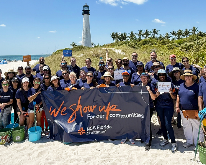 Group of HCA Healthcare volunteers cleaning up the beach and posing for a photo