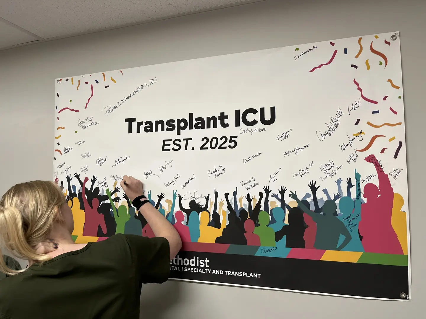 Staff member signing the Transplant ICU celebratory banner.