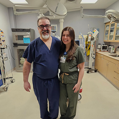 Dr. Peter Dourdoufis and his daughter Maddie smile for the camera in front of lab equipment.