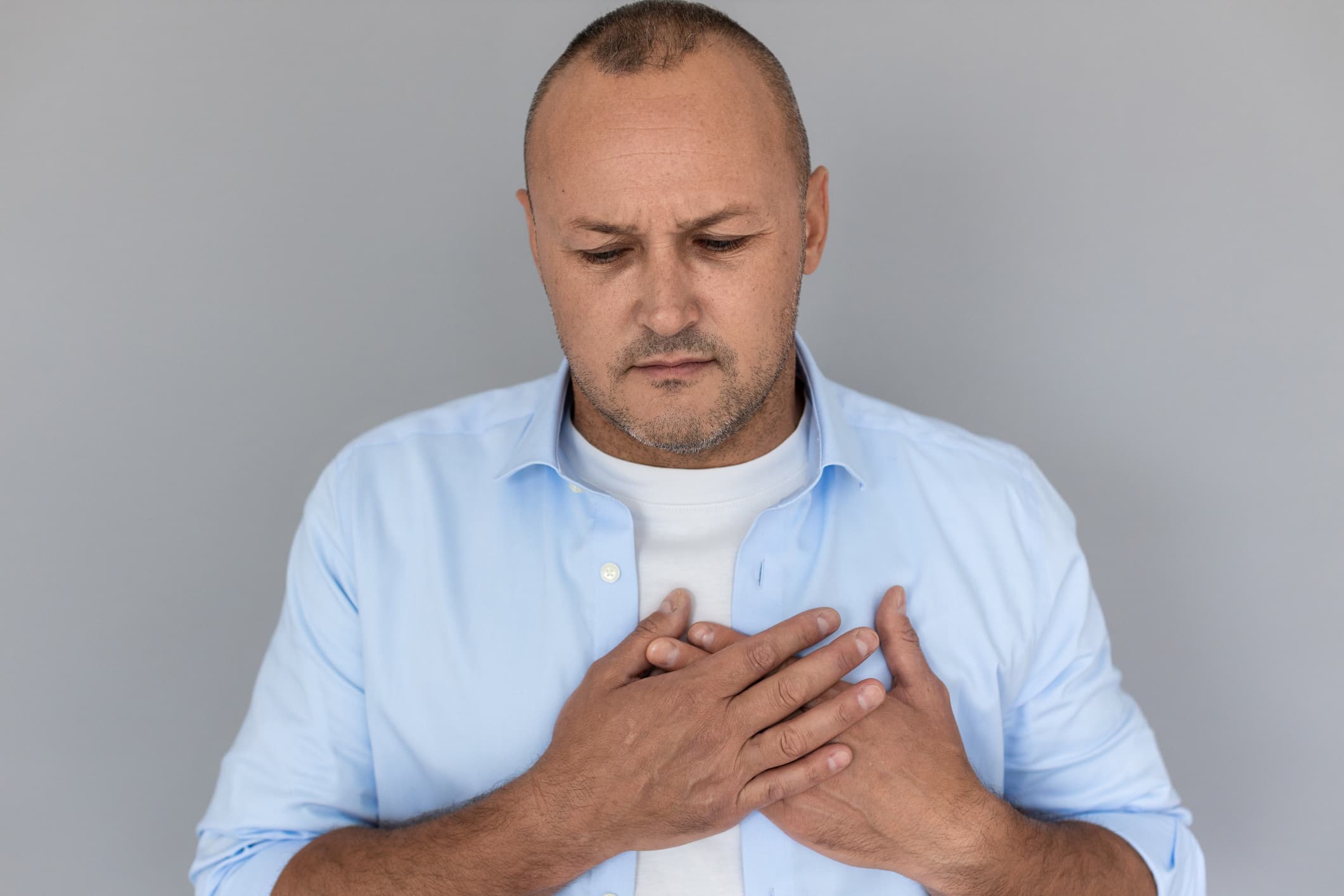 Middle aged man with acid reflux symptoms holding his hand to his chest