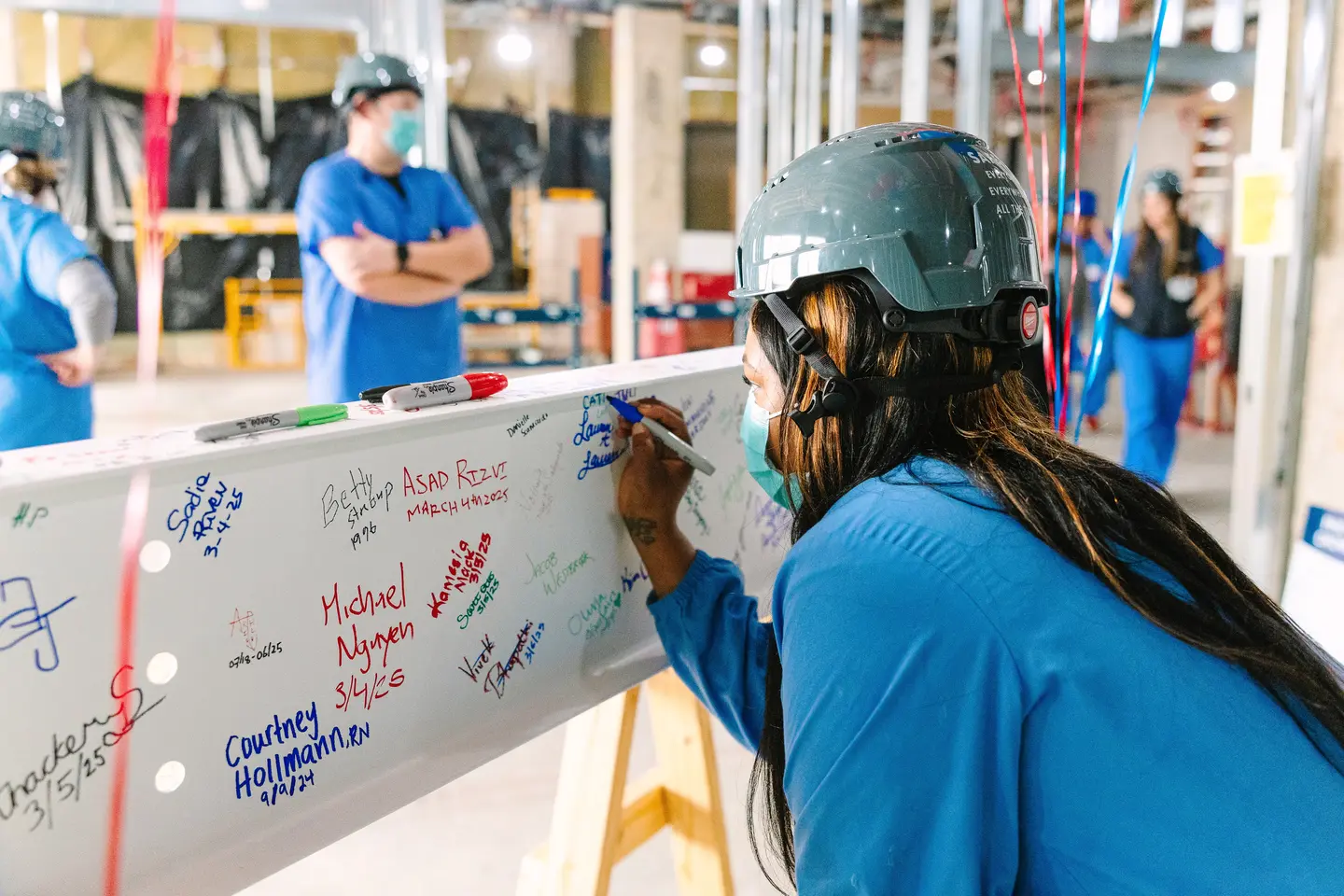 Over the shoulder photo of team member signing the beam.