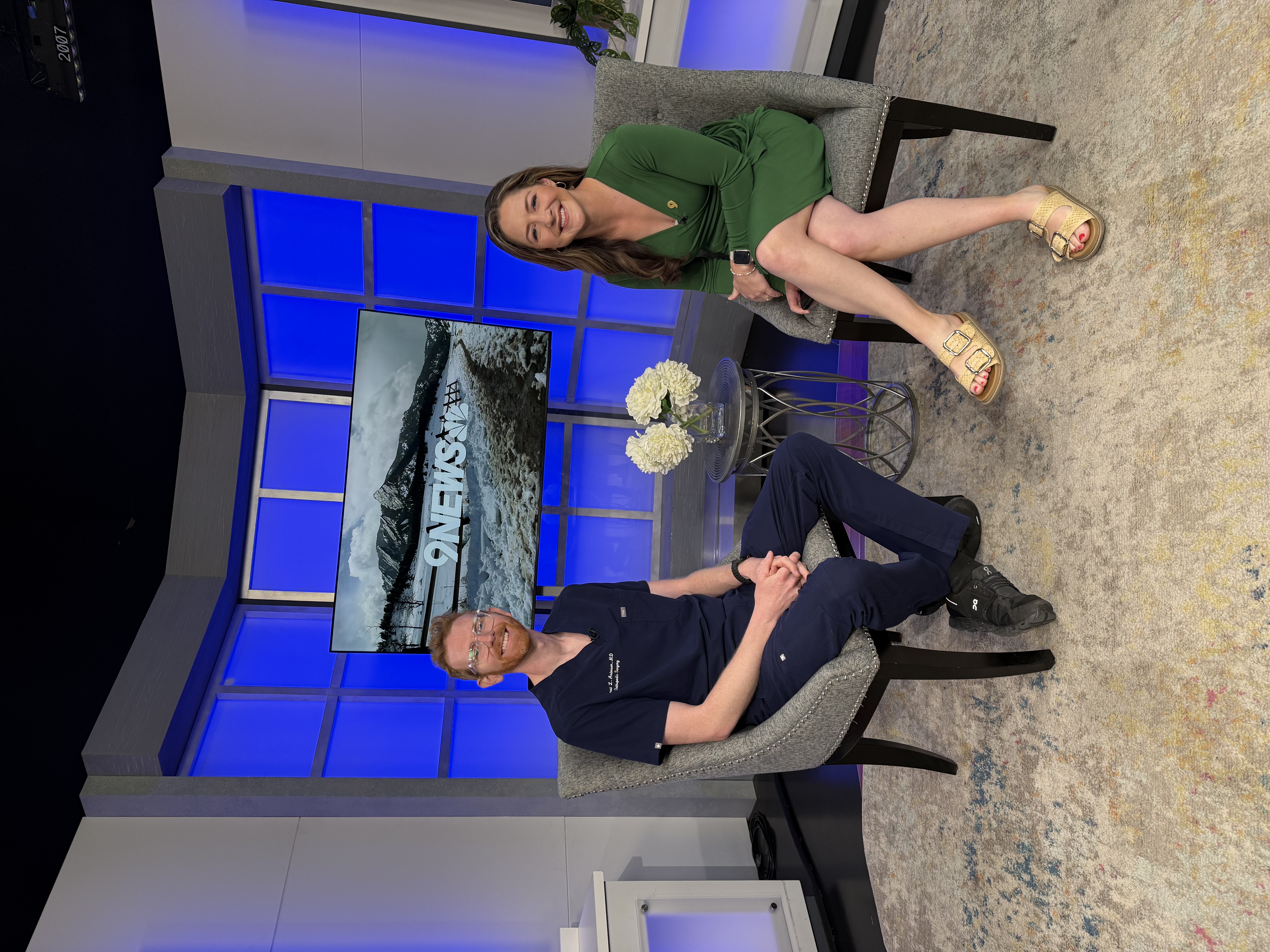 Dr. Anderson smiling with the host on a set of 9News.
