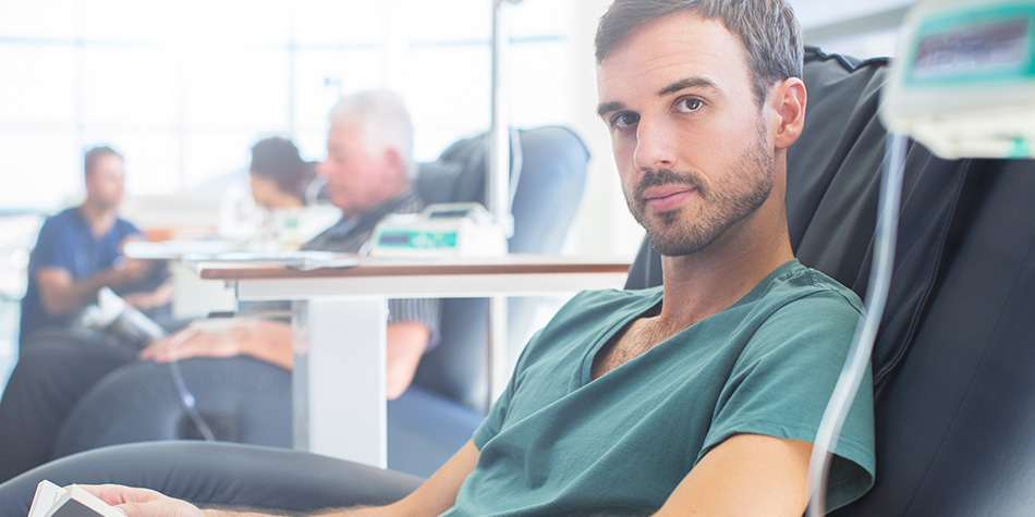 Man sitting in a chair receiving a chemotherapy treatment. 