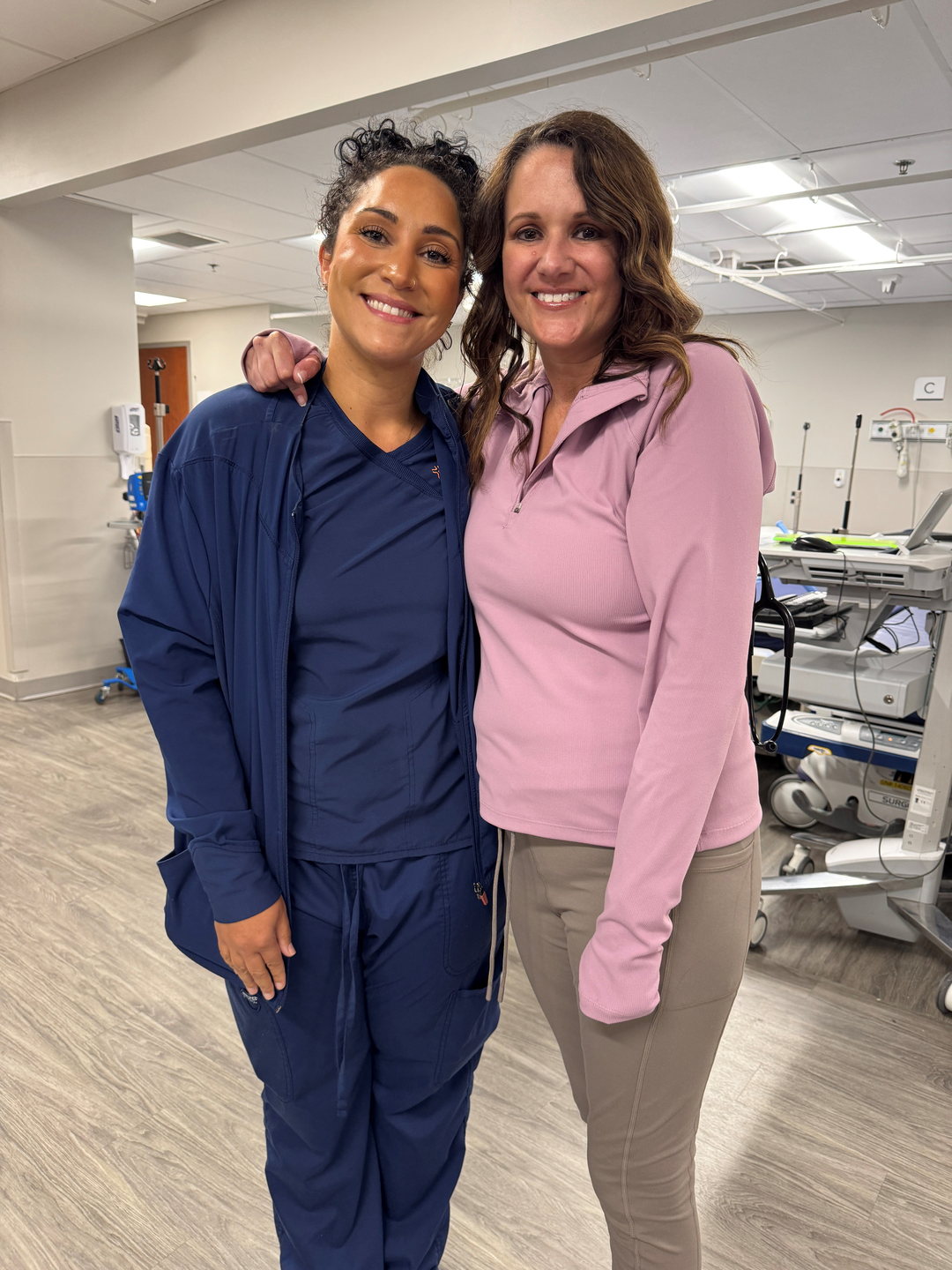 Woman stands smiling and hugging nurse.