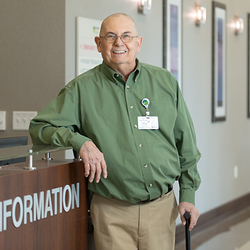 Chip Hennequin smiles while standing next to the information desk at Lee's Summit Medical Center.