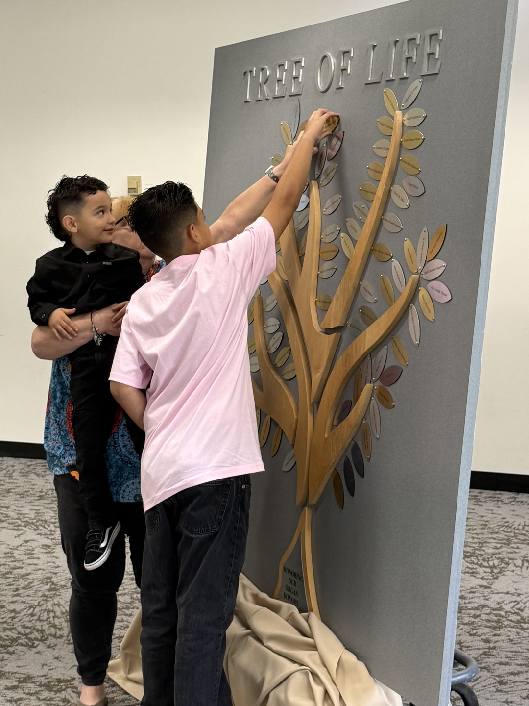 Family placing a leaf with a donors name on the tree of life.