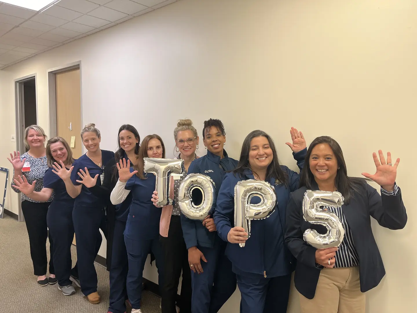 Methodist hospital physicans and staff posing for group photo with balloons spelling out T-O-P-5.