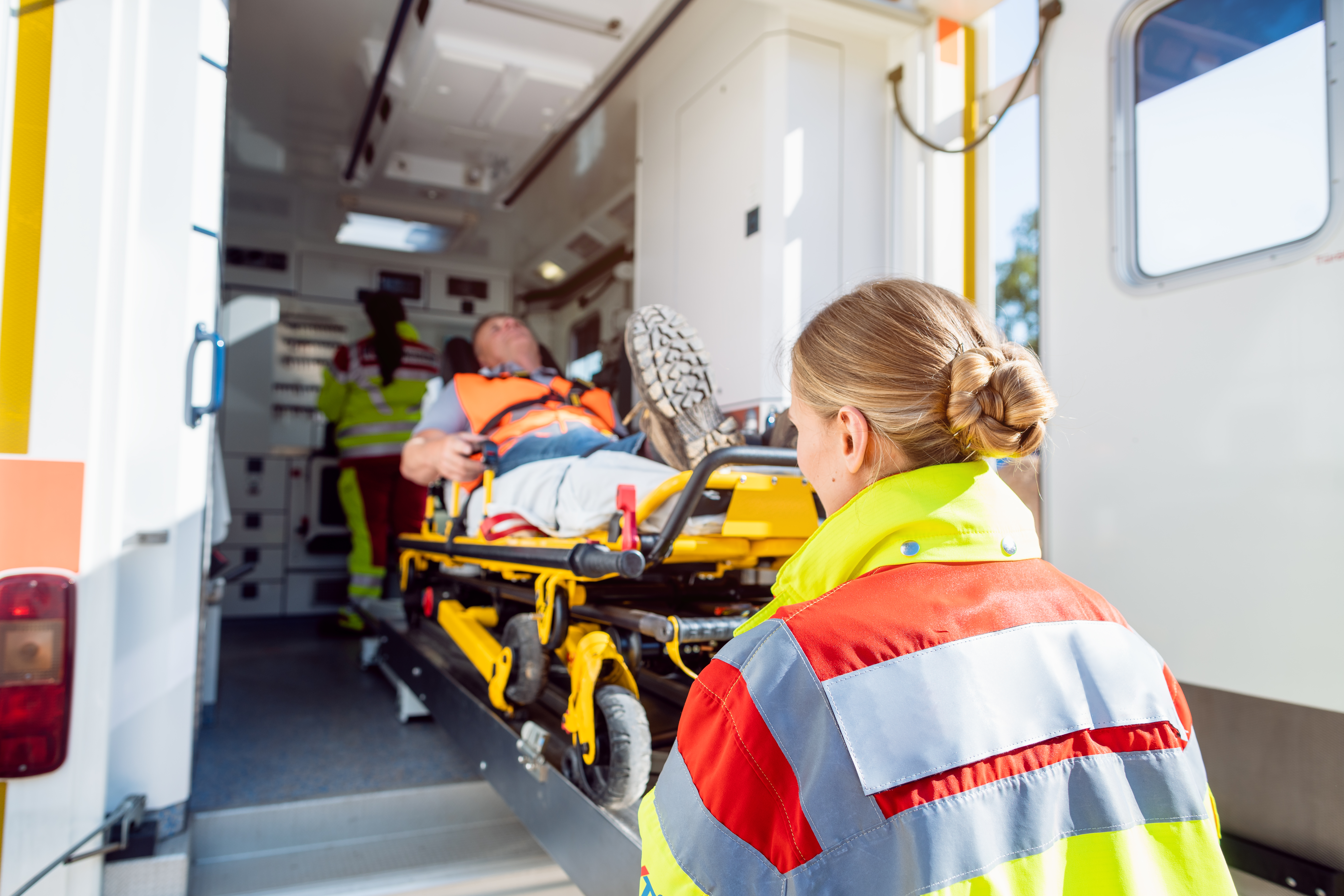 A female EMT loads patient into an ambulance