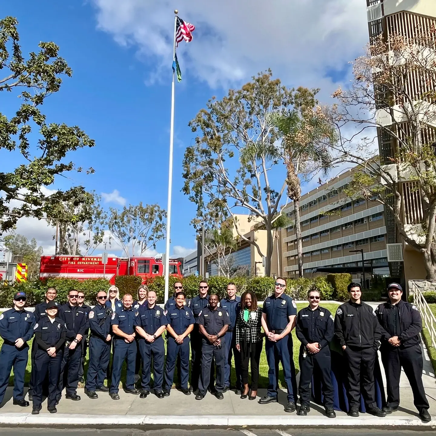 Medical professionals and first responders smile while standing together in front of Riverside Community Hospital.