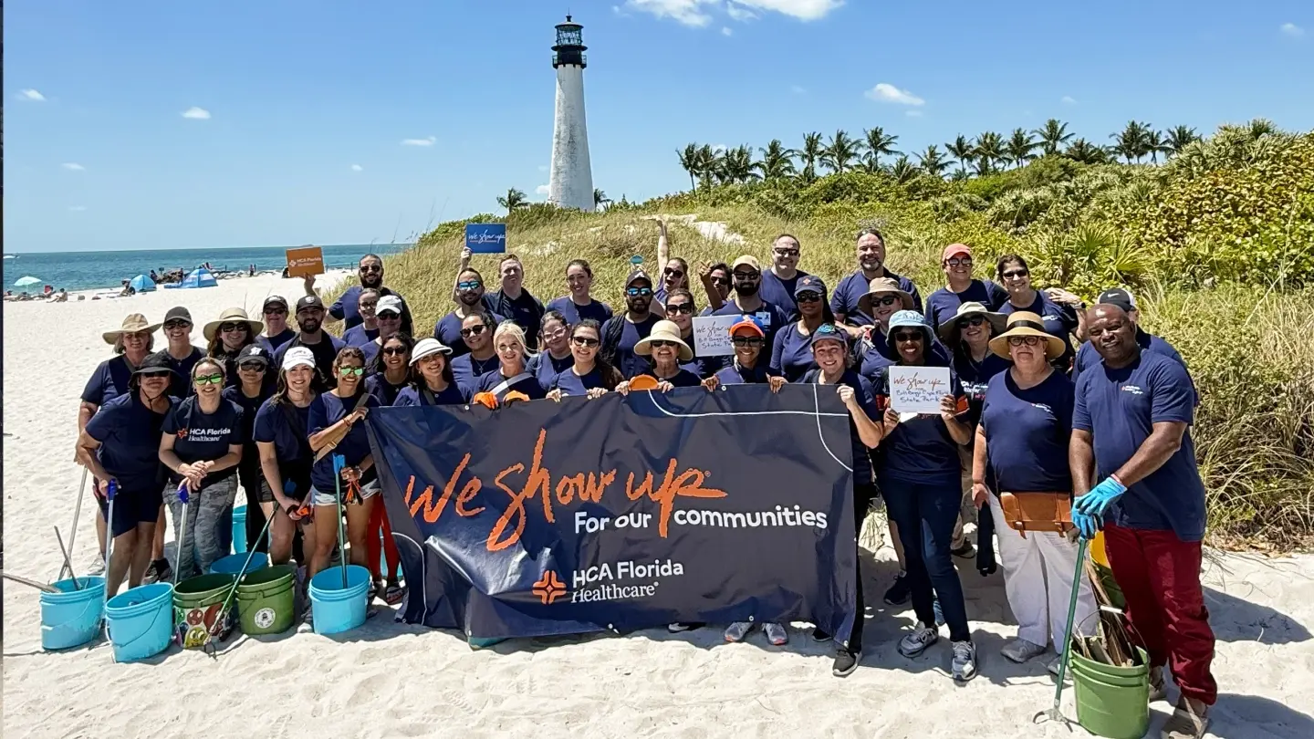 Group of HCA Healthcare volunteers cleaning up the beach and posing for a photo