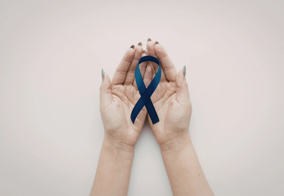 Hands hold a colorectal cancer awareness ribbon.
