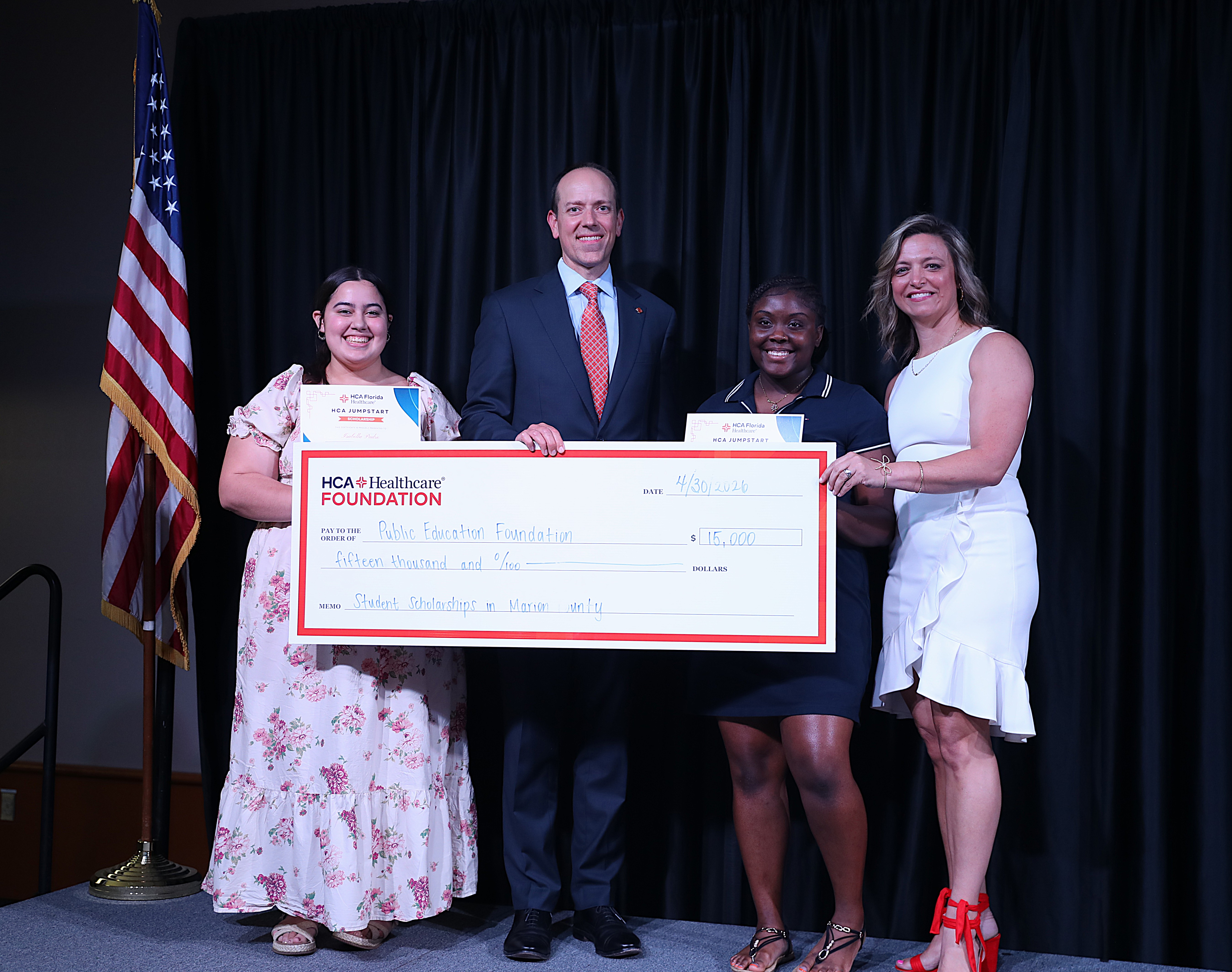 Ocala Hospital and Take Stock representatives, and two scholarship winners pose with $15,000 donation check.