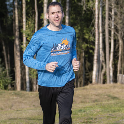 Daniel running outdoors, wearing a blue jogging shirt and black athletic pants.