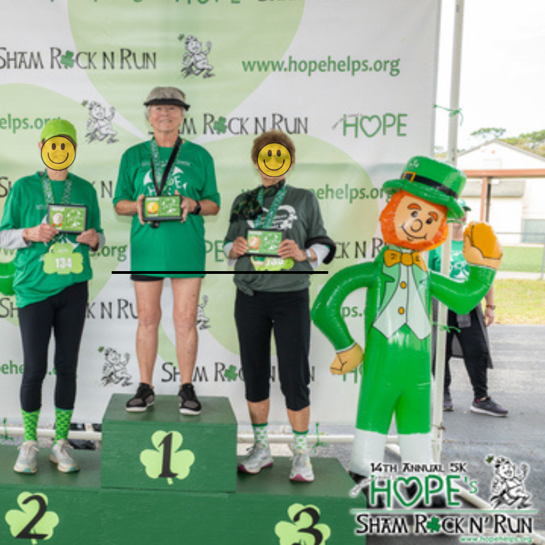 Sandy Hults standing on a #1  greenpedestal with 2 other people at 14th annual 5k Home Shamrock Run