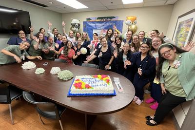 Methodist staff posing in meeting room in front of celbratory cake for AACN Beacon Award for Excellence.