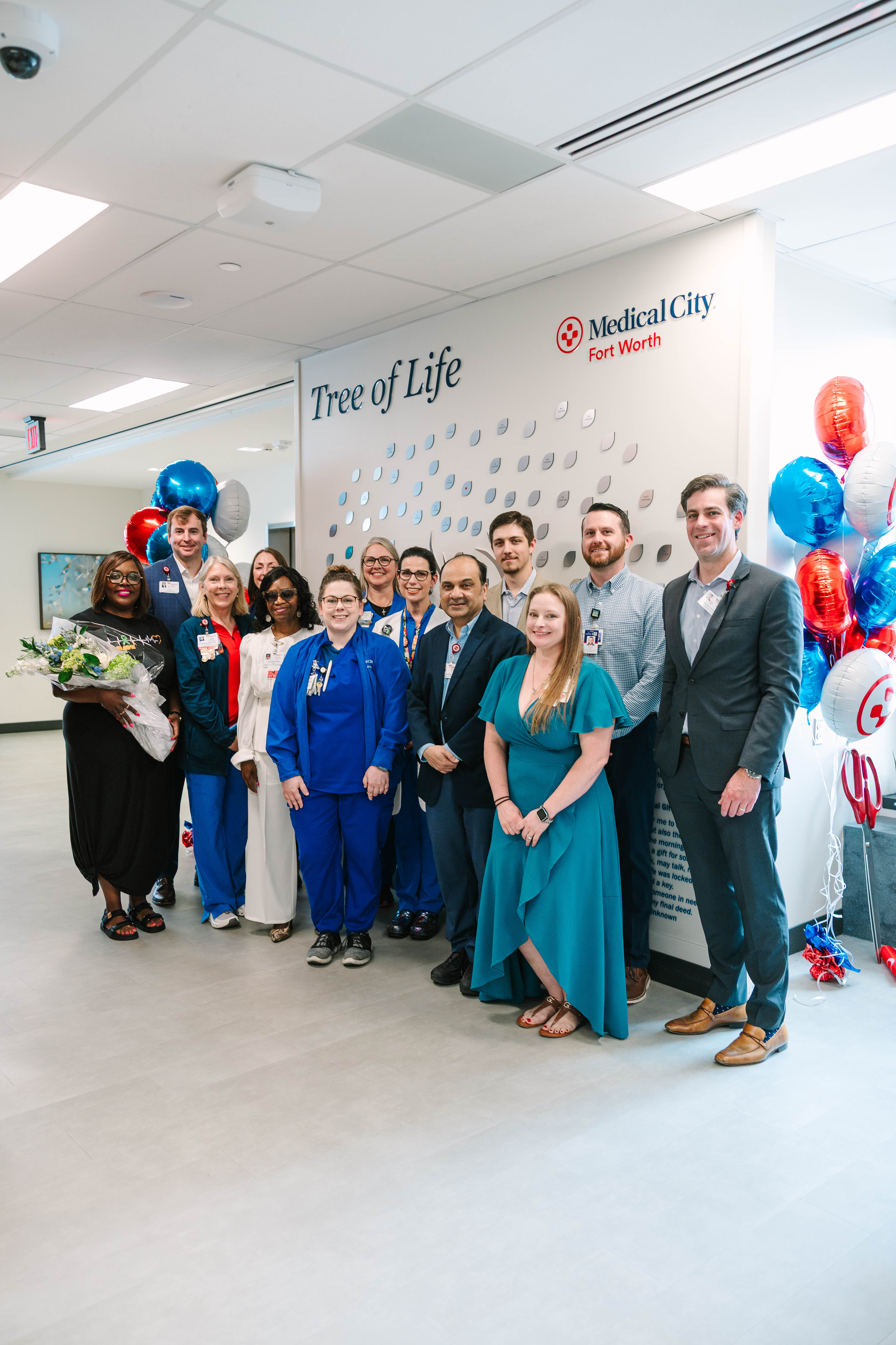 Medical City Fort Worth colleagues and guests gather by the "Tree of Life." The display features a striking design with engraved leaves, each bearing the name of an organ donor.