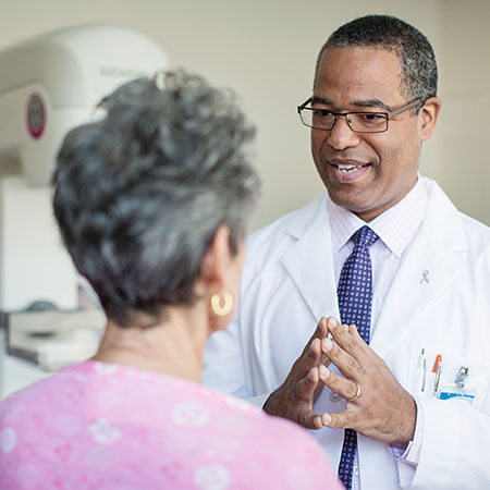 A physician speaks with a patient in an exam room.