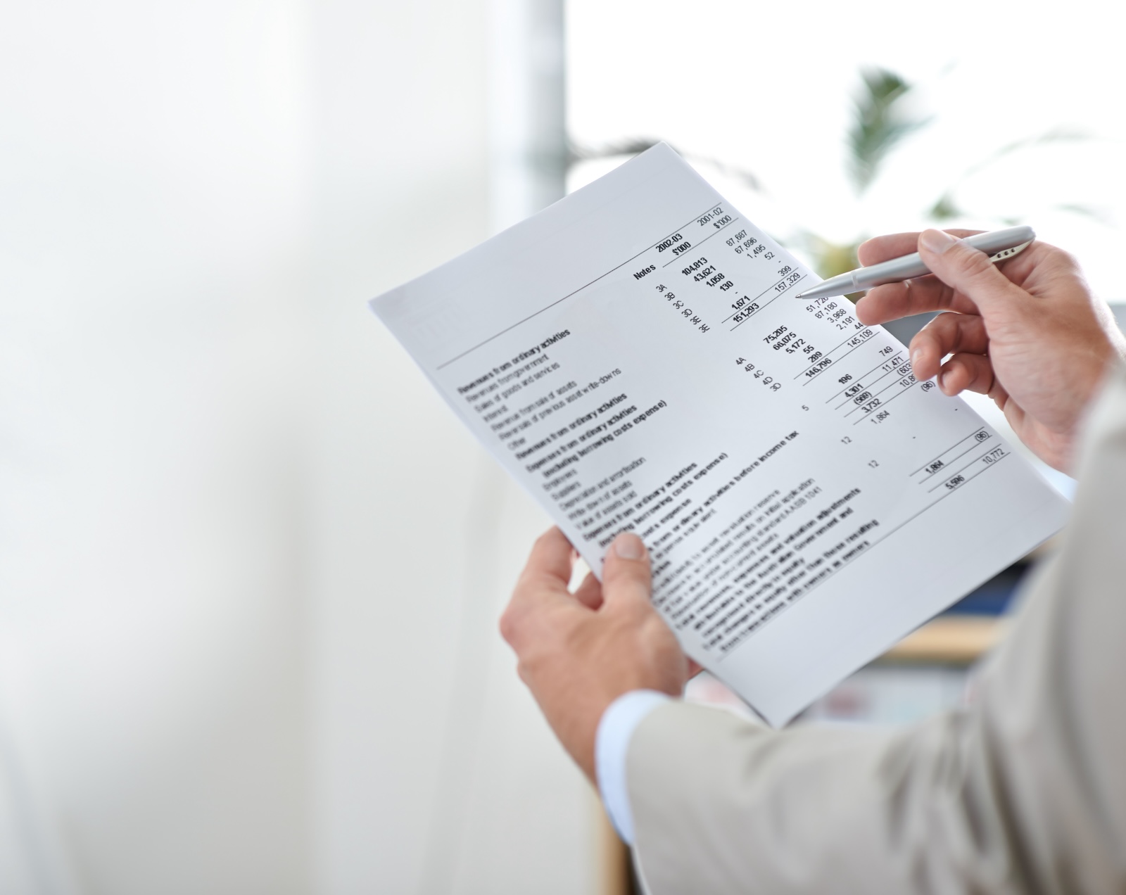 A person with a pen in their right hand reading a hospital bill.
