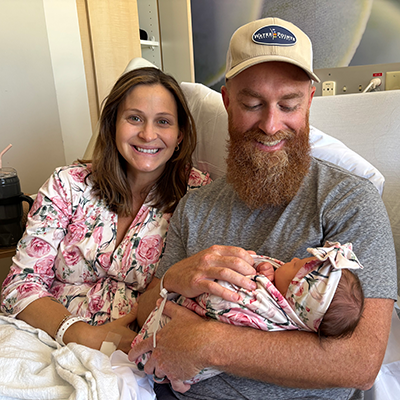 Jessie and Austin holding baby Francie and smiling in hospital.