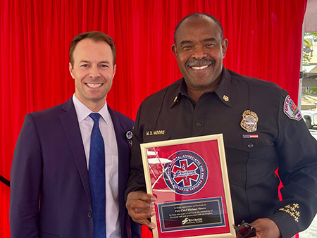 Fire Chief Michael Moore smiles while holding a commemorative plaque for his service as a first responder.