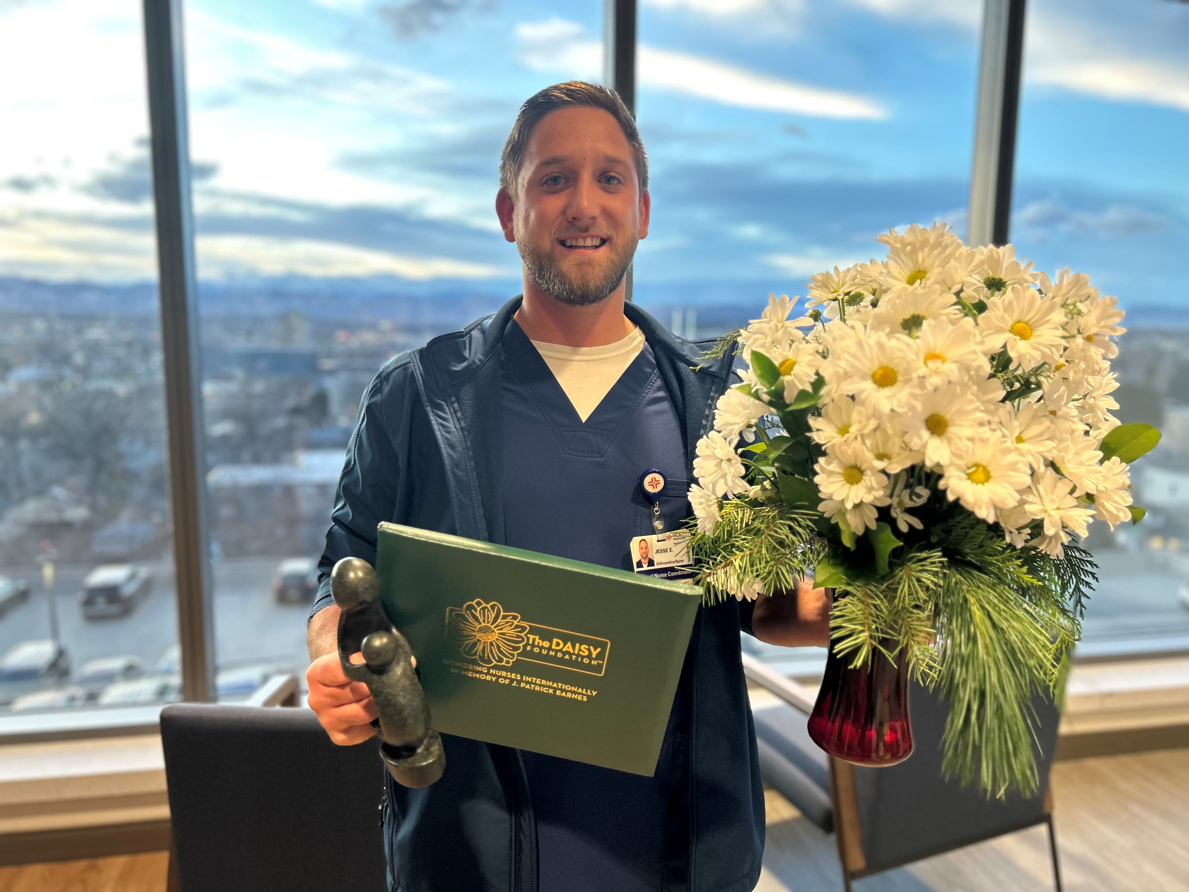 Jesse Ellis, RN at HealthONE Swedish holds his DAISY Award.
