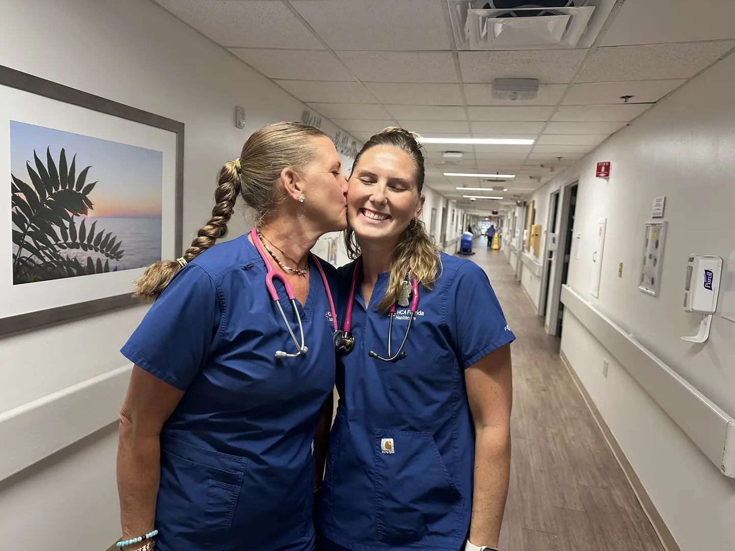 In scrubs, Lily Bakulski gives her mother Molly a kiss on the cheek in an Englewood Hospital hallway.