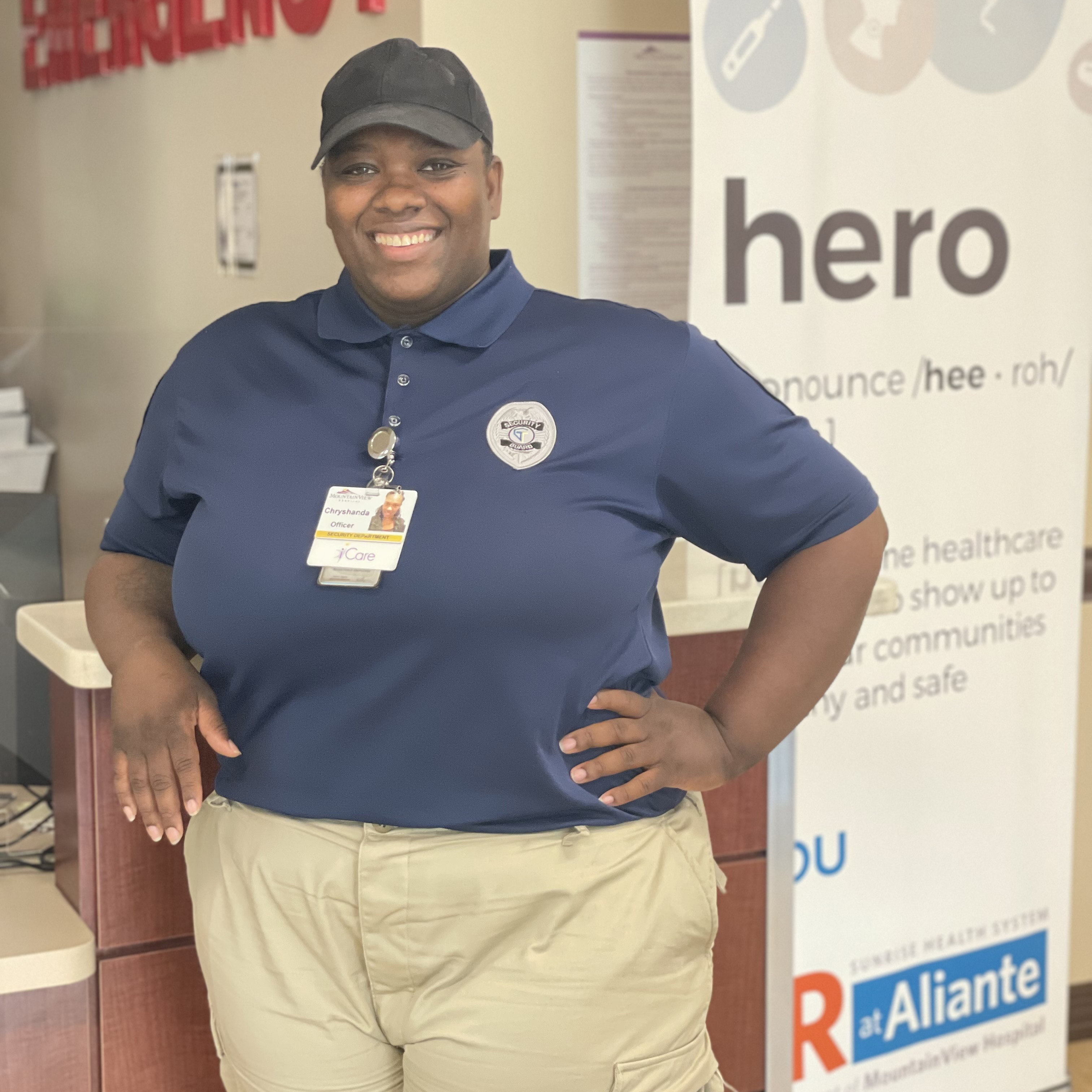 Security officer stands in front of a desk with a smile on her face.