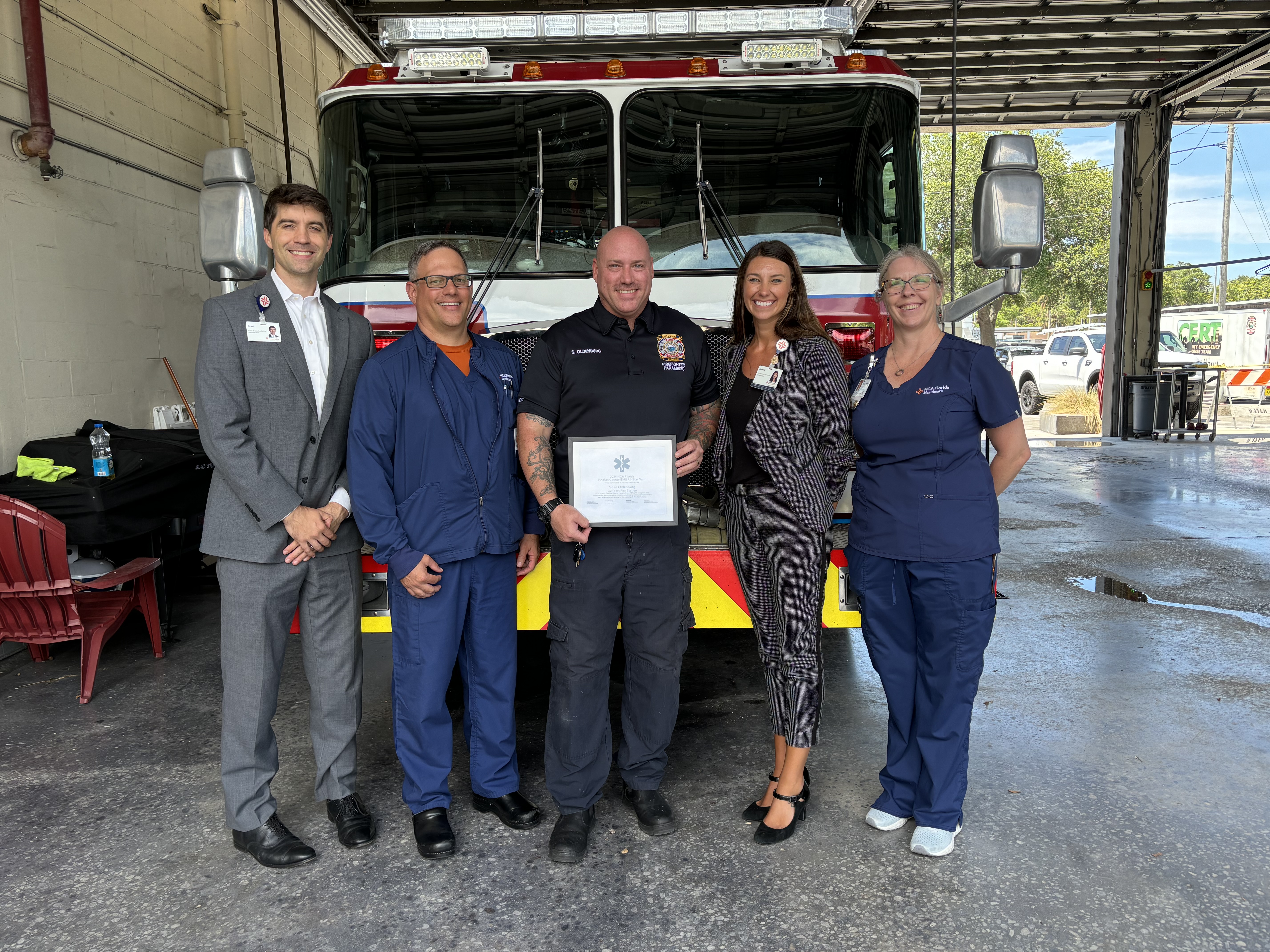 HCA leadership meets with Sean Oldenburg to present his EMS All-Star Award, which he holds in the center of the group photo.