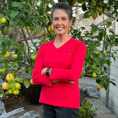 Melissa Silver smiles, while standing in front of a citrus tree outdoors.