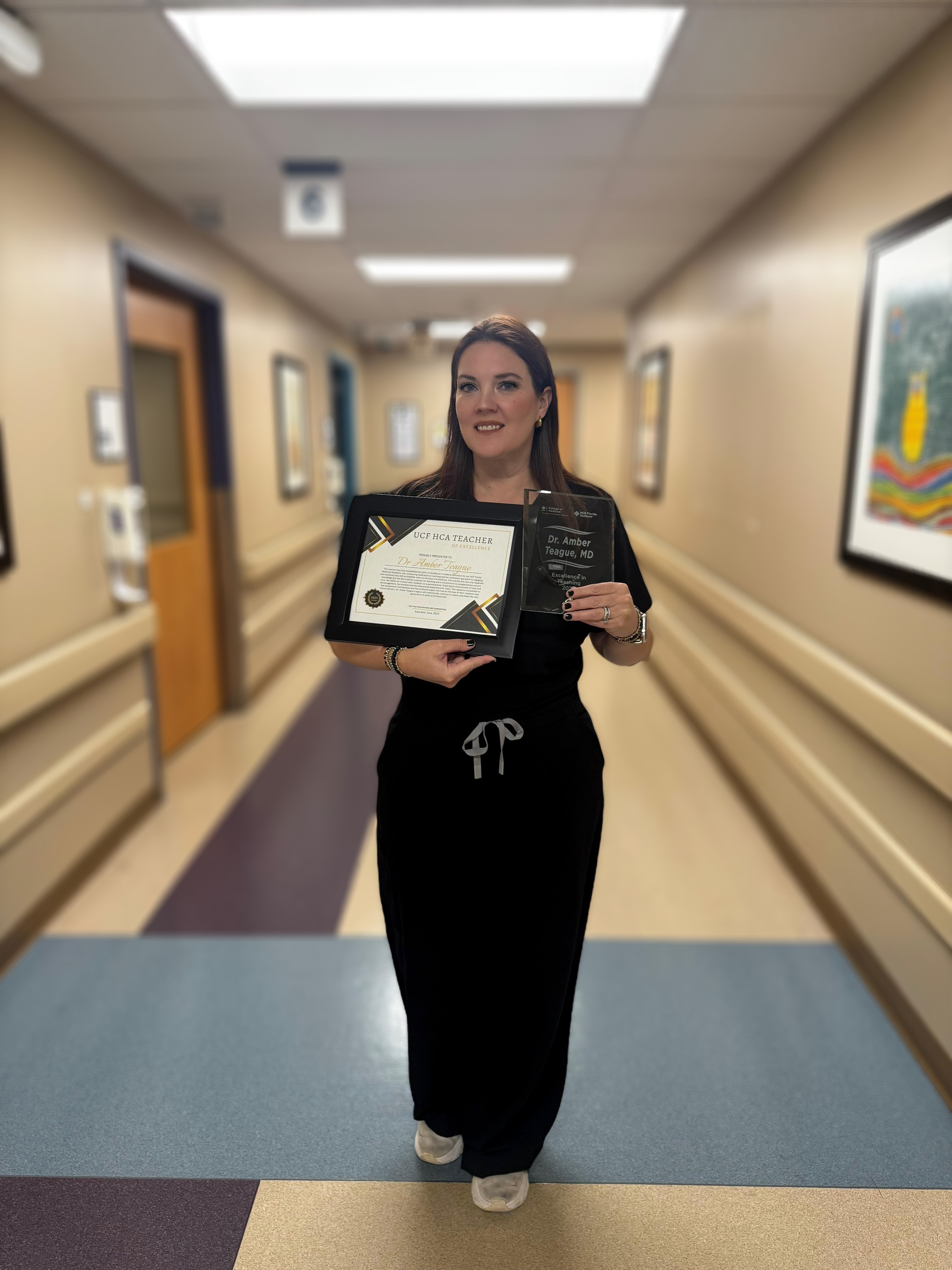 Dr. Amber Teague in hospital hallway displaying her awards.
