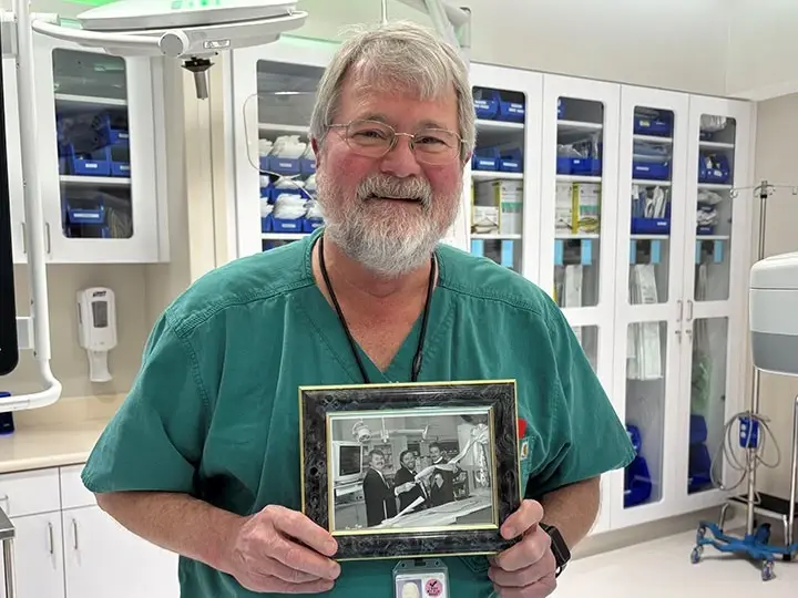 Dr. Stoll in Methodist Northeast Hospital, holding a framed picture, posing and smiling.