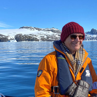 Gary on a boat with icy mountains in the background.