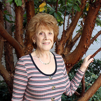 Stroke survivor Diana Beserra smiles in front of a tree outdoors.