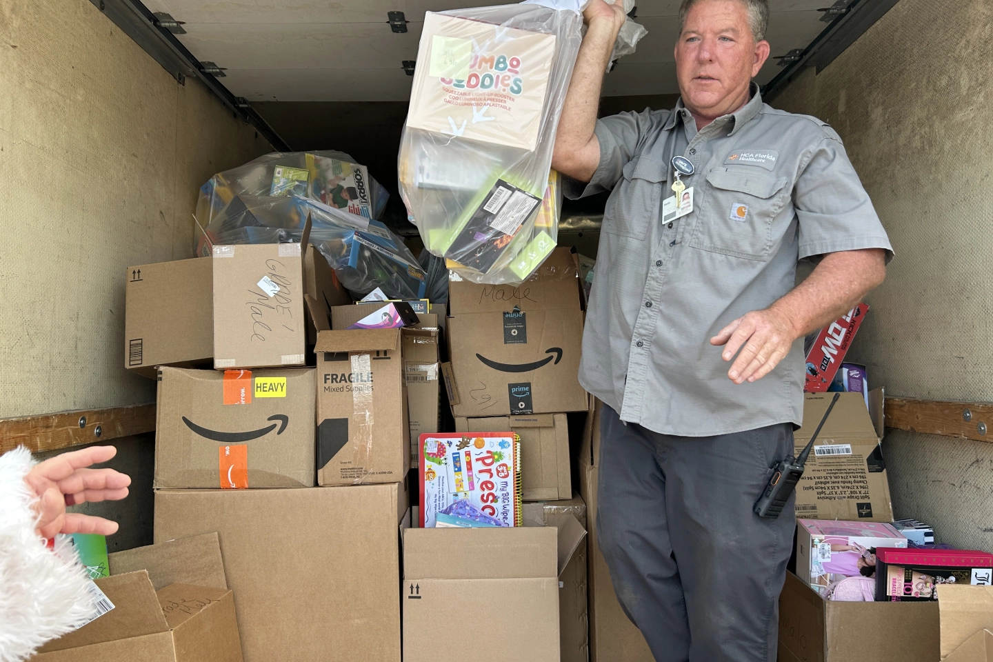 Hospital worker handing gifts off truck to Santa