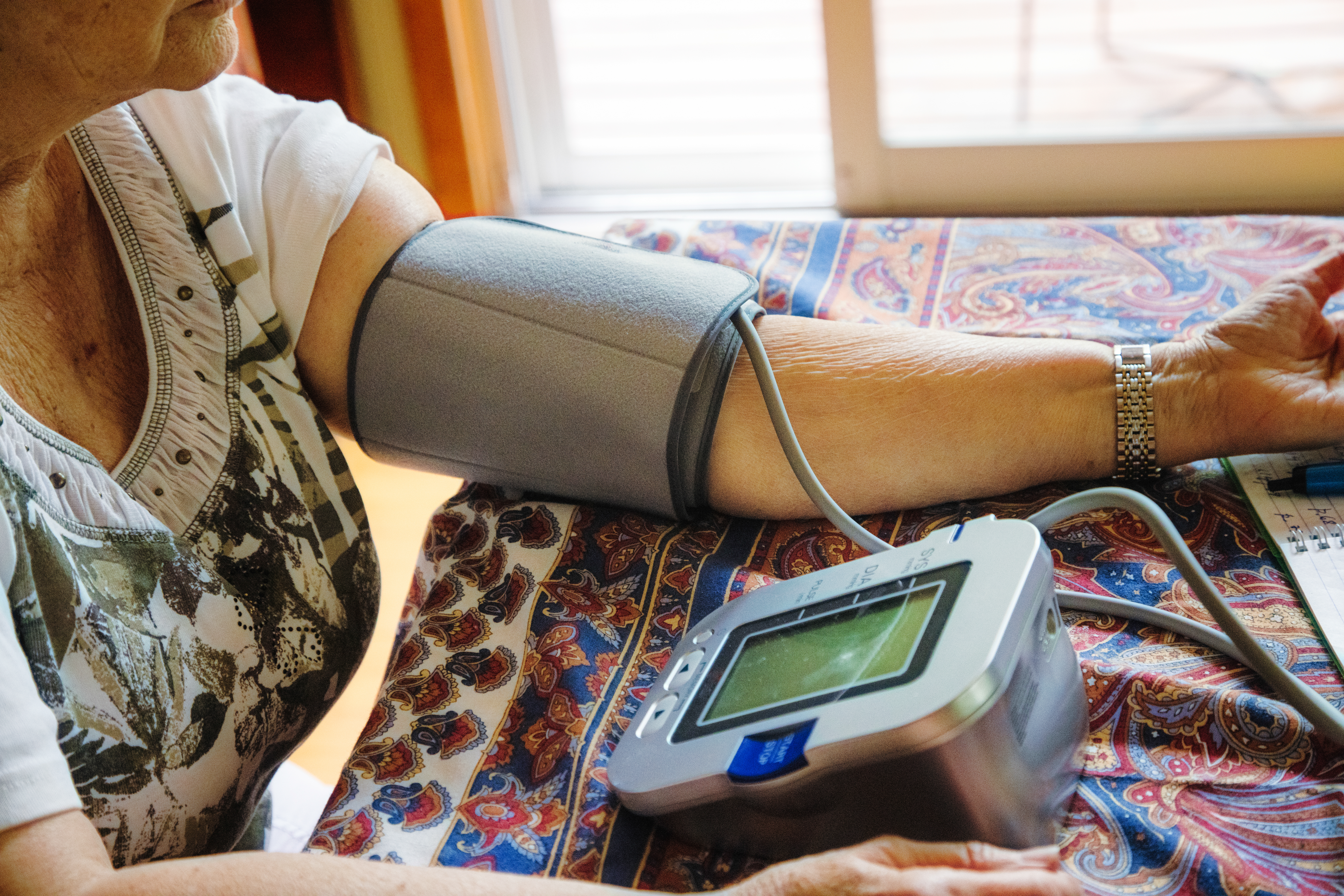 Close-up on senior woman's arm as she measures her blood pressure at home with monitoring equipment
