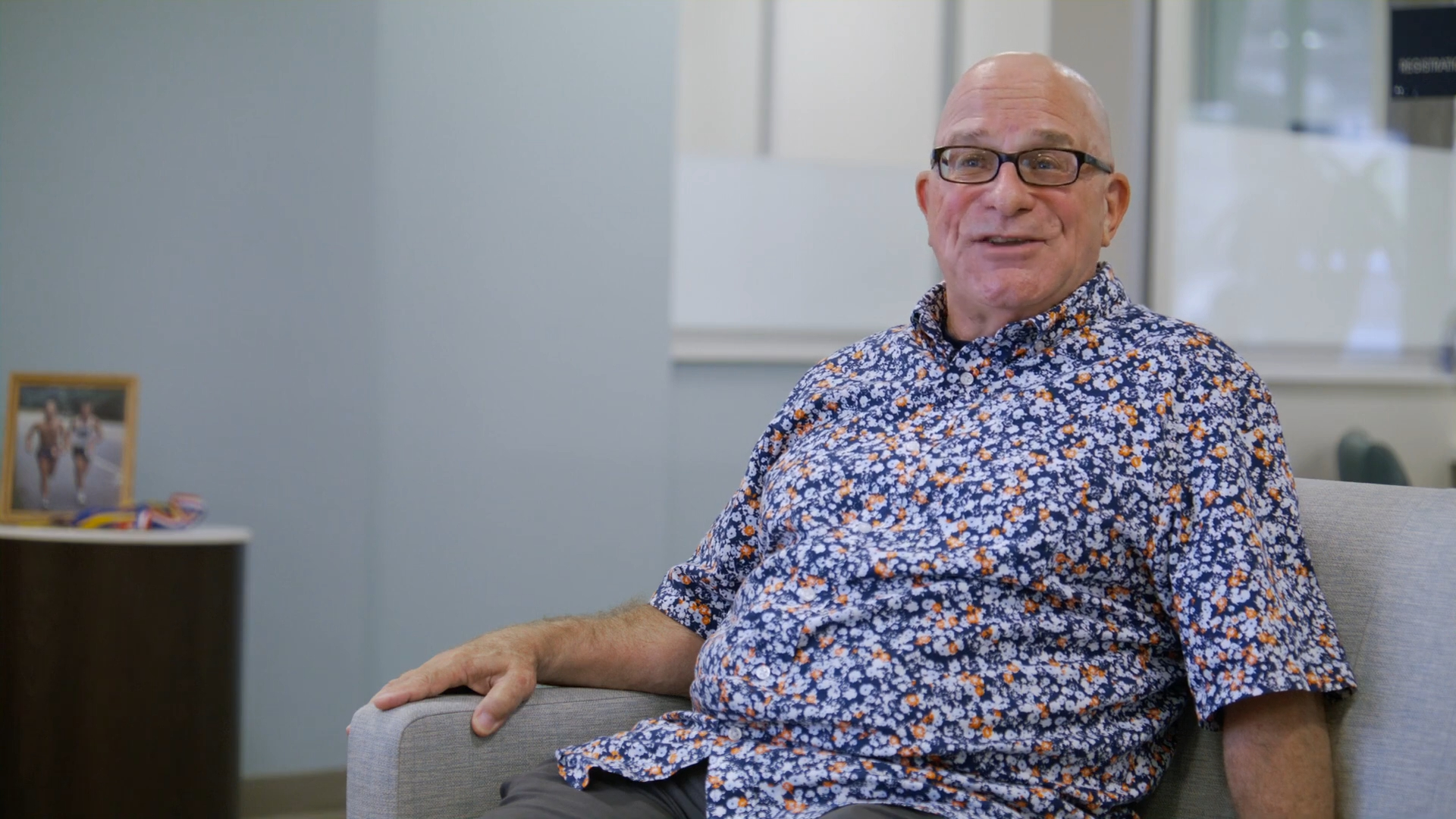 Cancer survivor and marathon runner Brian Butler sitting on a couch, smiling.