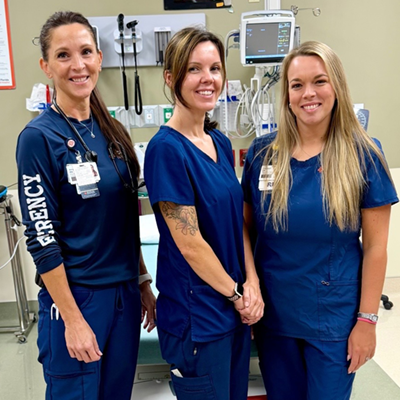 Three caregivers who helped Russell Darwin pose for a photo