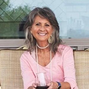 Cancer survivor Leslie Pickus smiles while holding a glass of wine.