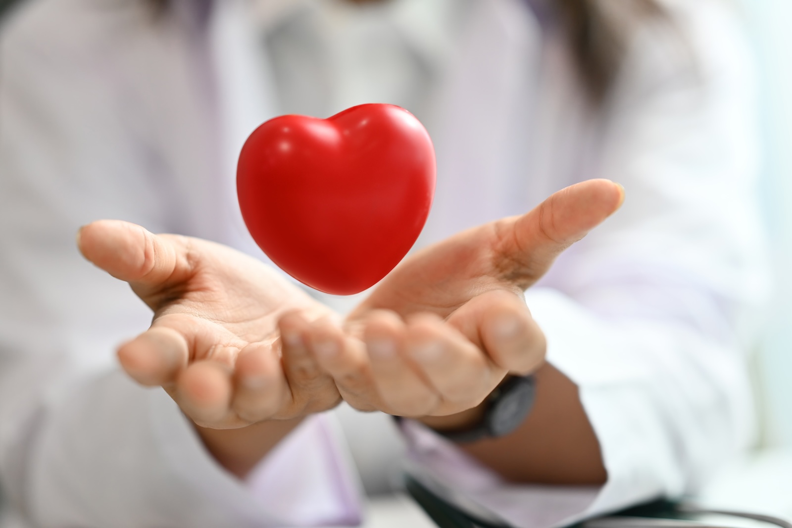 A heart floating over a person's two clasped hands.