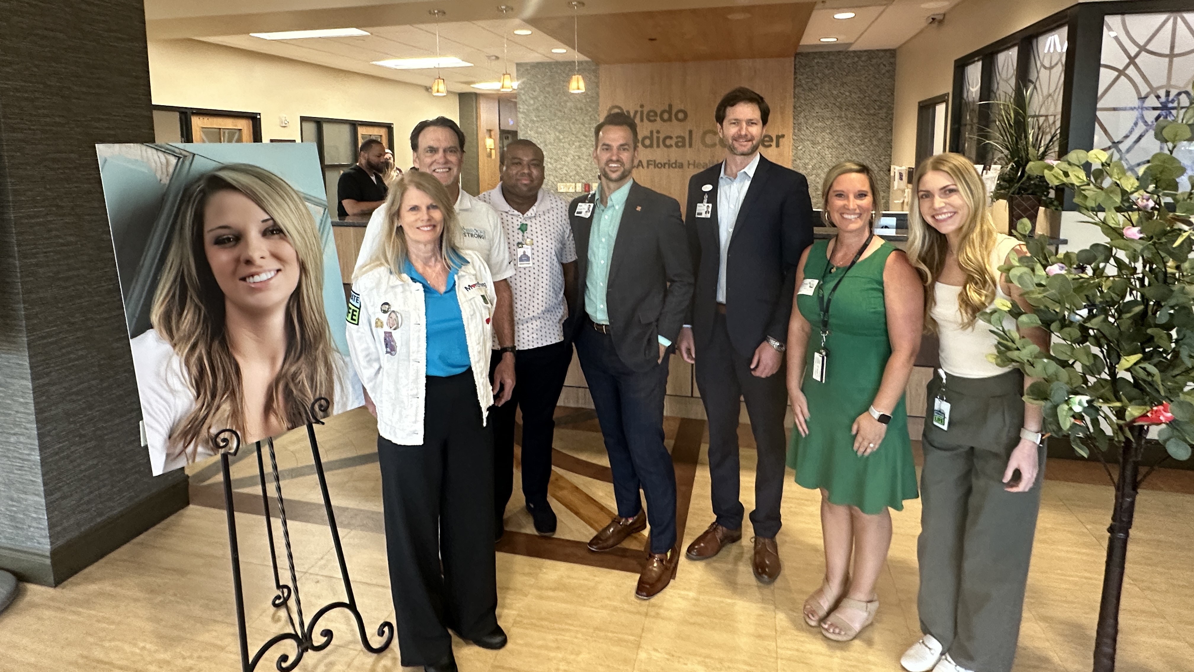 Hospital staff and donor family at a special ceremony event with a photo of a donor.