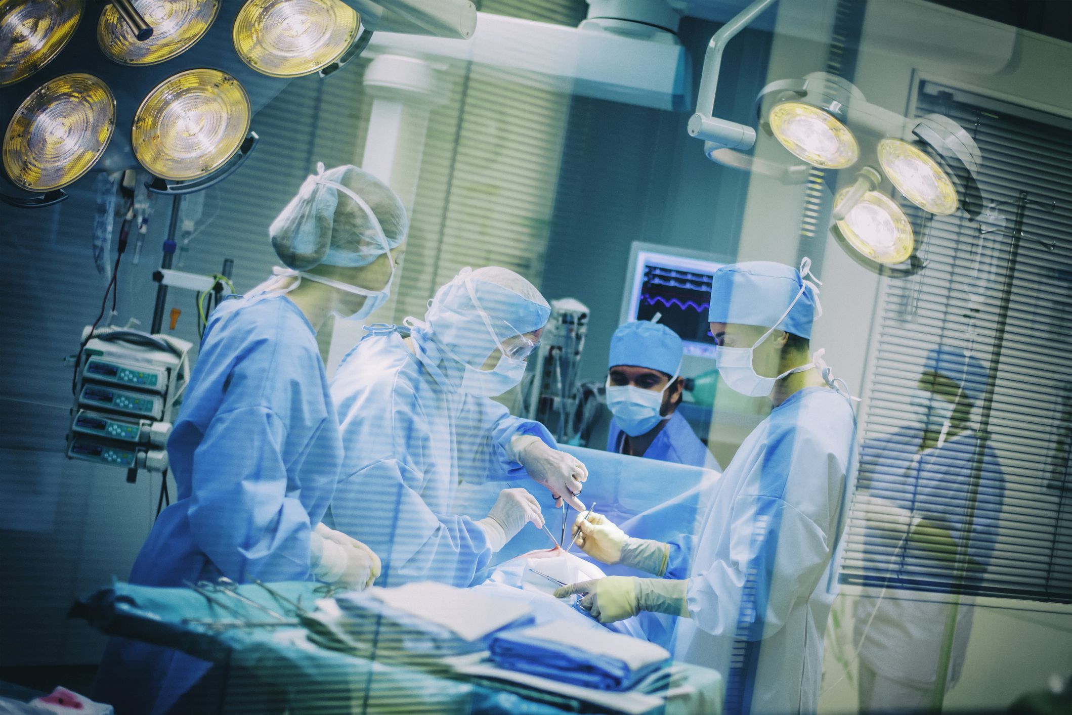 Operating room team through window glass blinds