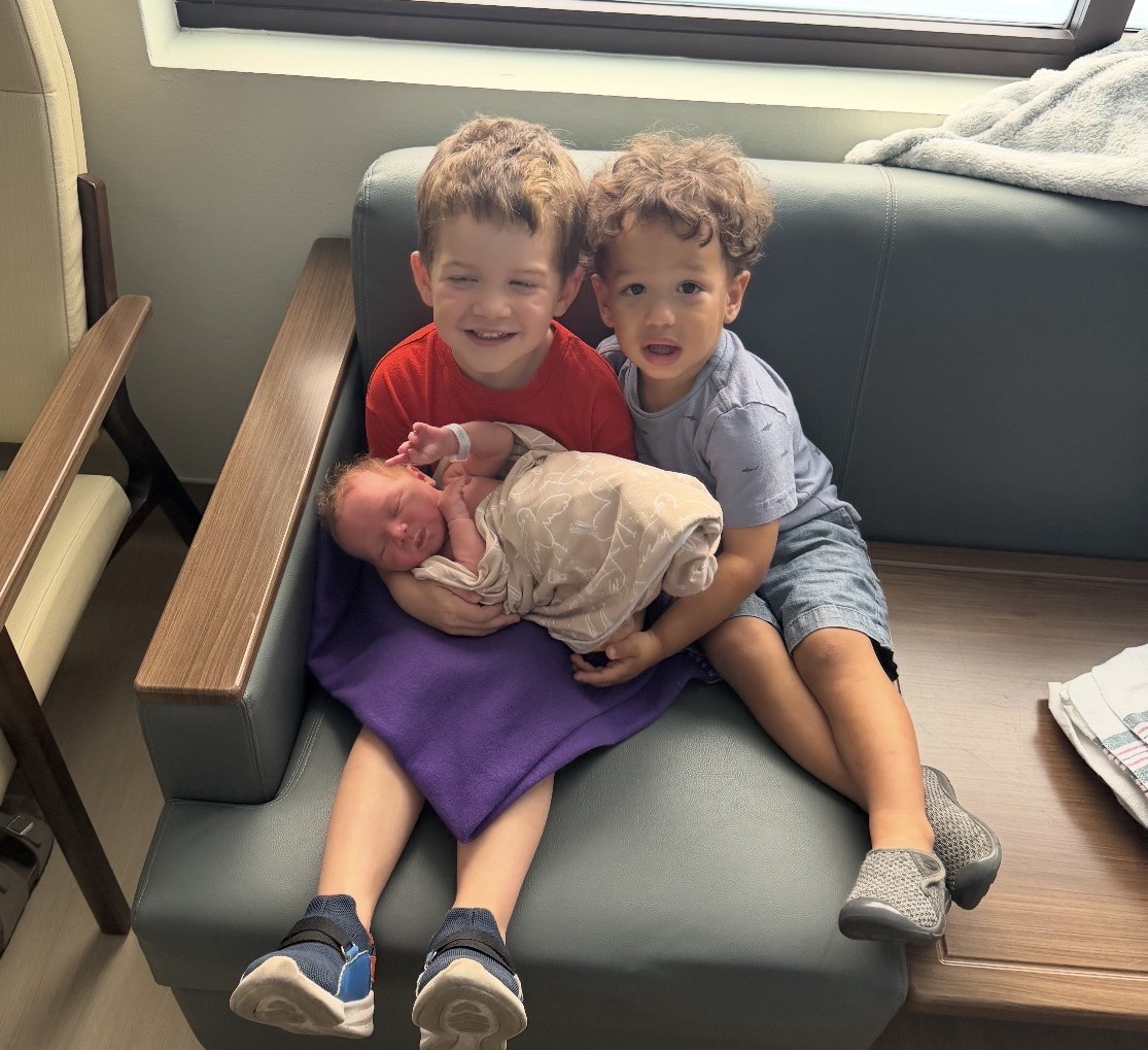 Young boys holding their new baby sister.