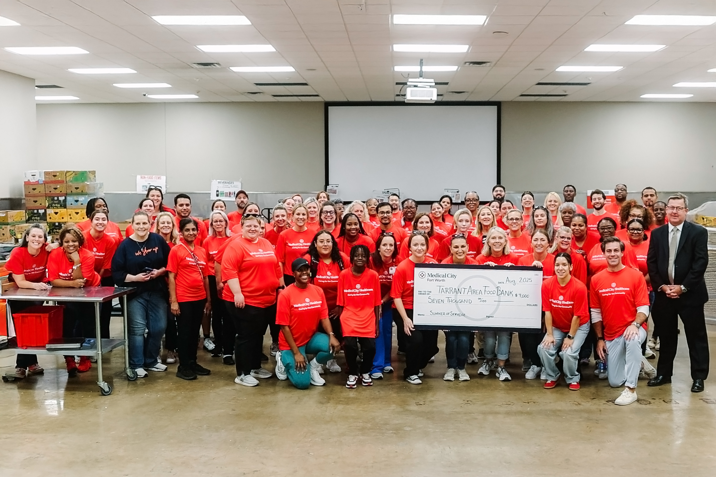 Medical City Fort Worth colleagues pose holding a donation check at the Tarrant Area Food Bank
