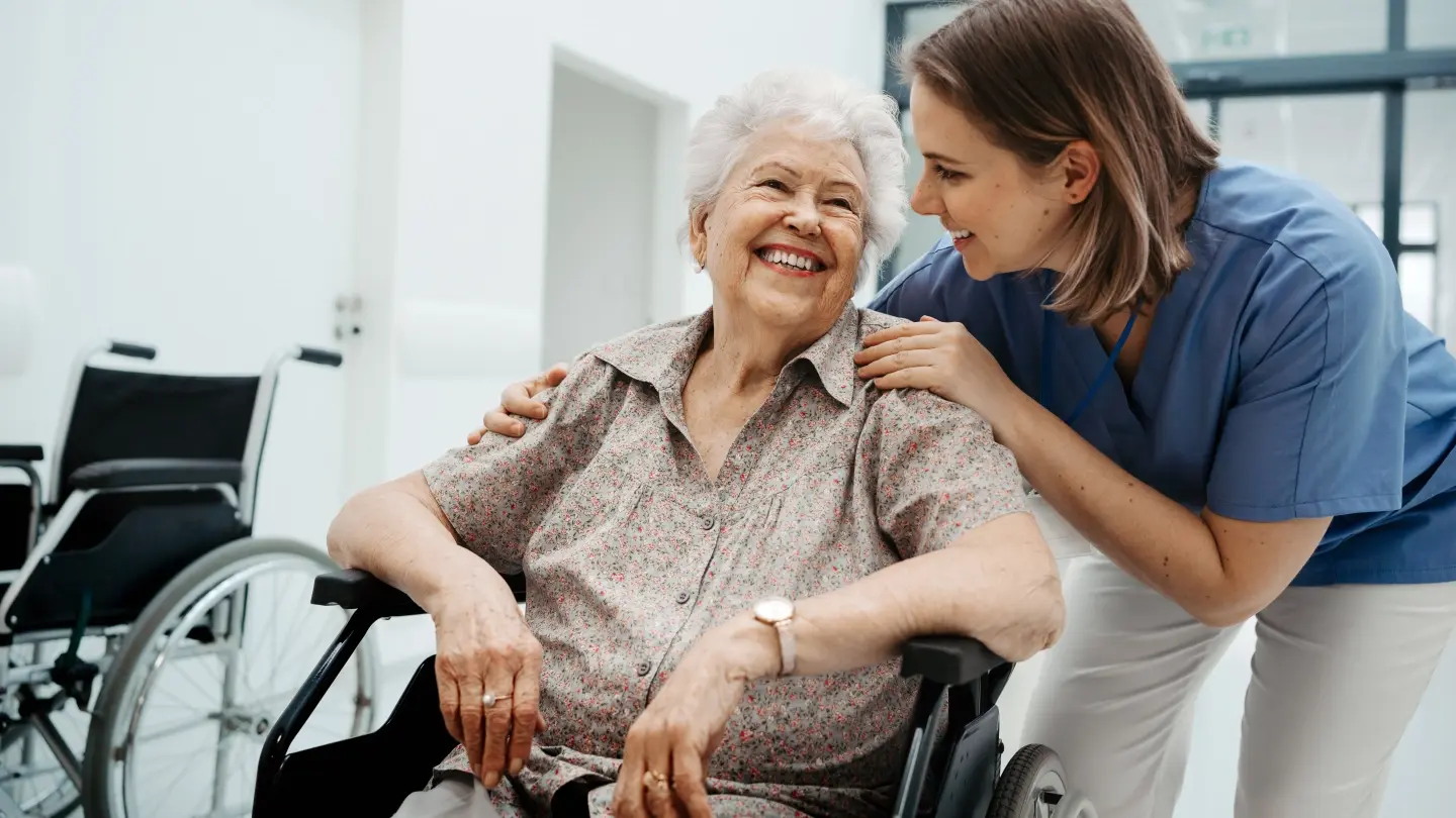Nurse placing hands on elderly patient's shoulders.