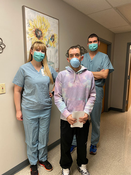 Matt Maddux, David's brother, smiles while standing with two members of his surgical team.