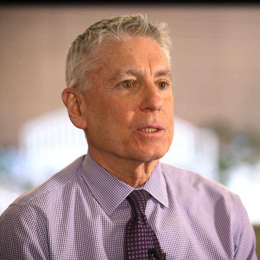 Paul Bakanowski talks about his experiences at Rose Medical Center during an interview where he is wearing a purple button-up shirt and tie.