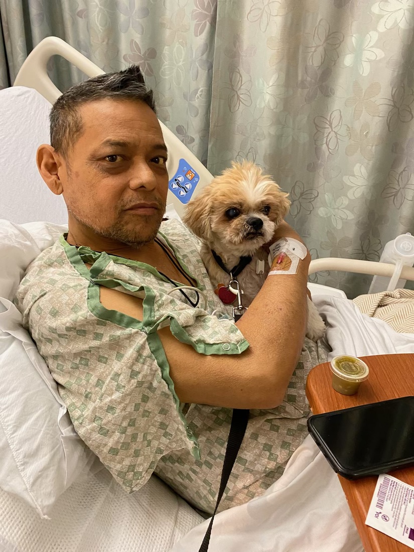 Arthur Guzman pre transplant sitting in a hospital bed holding a dog.