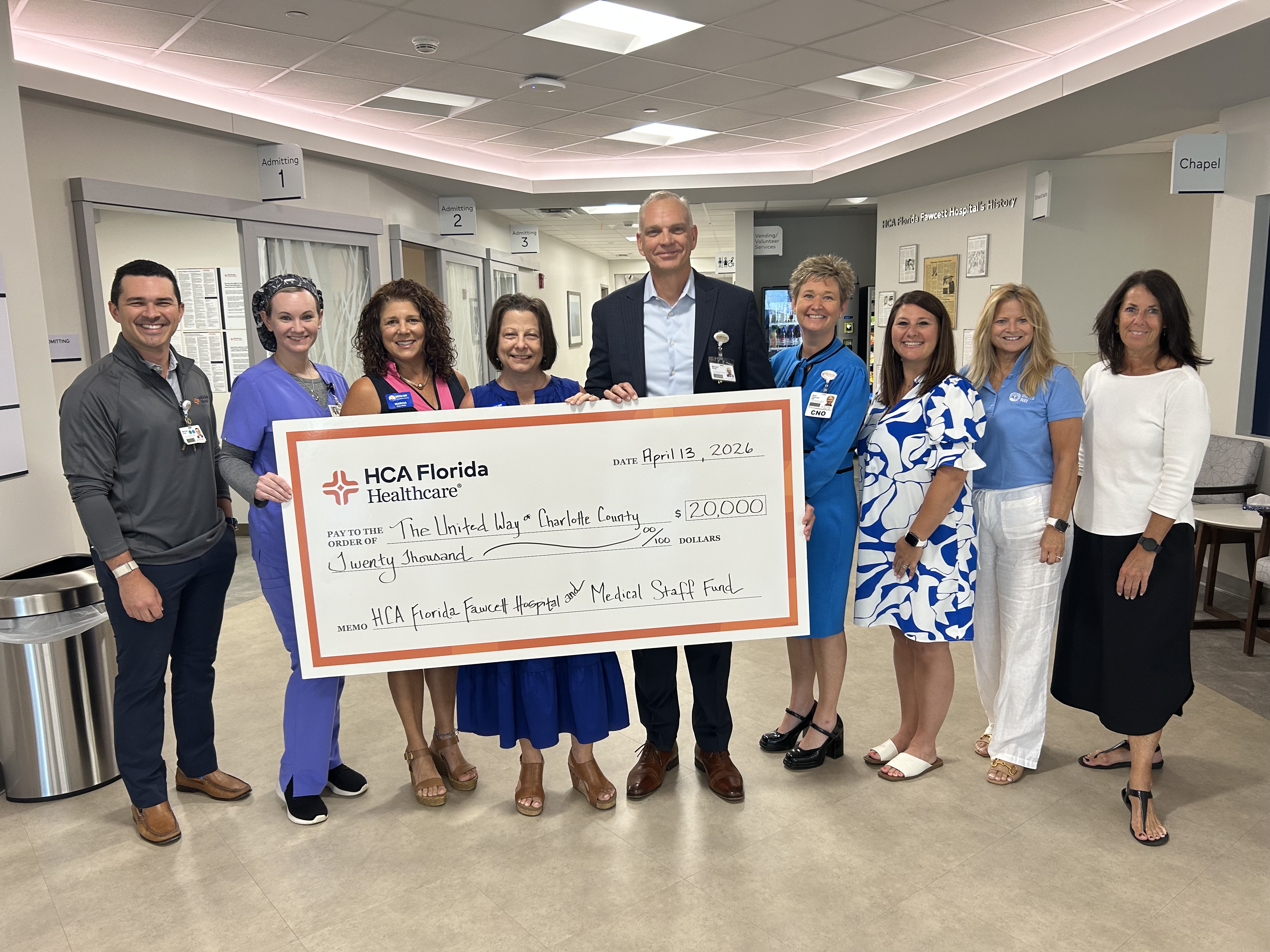 A group of people stand with a check for United Way.