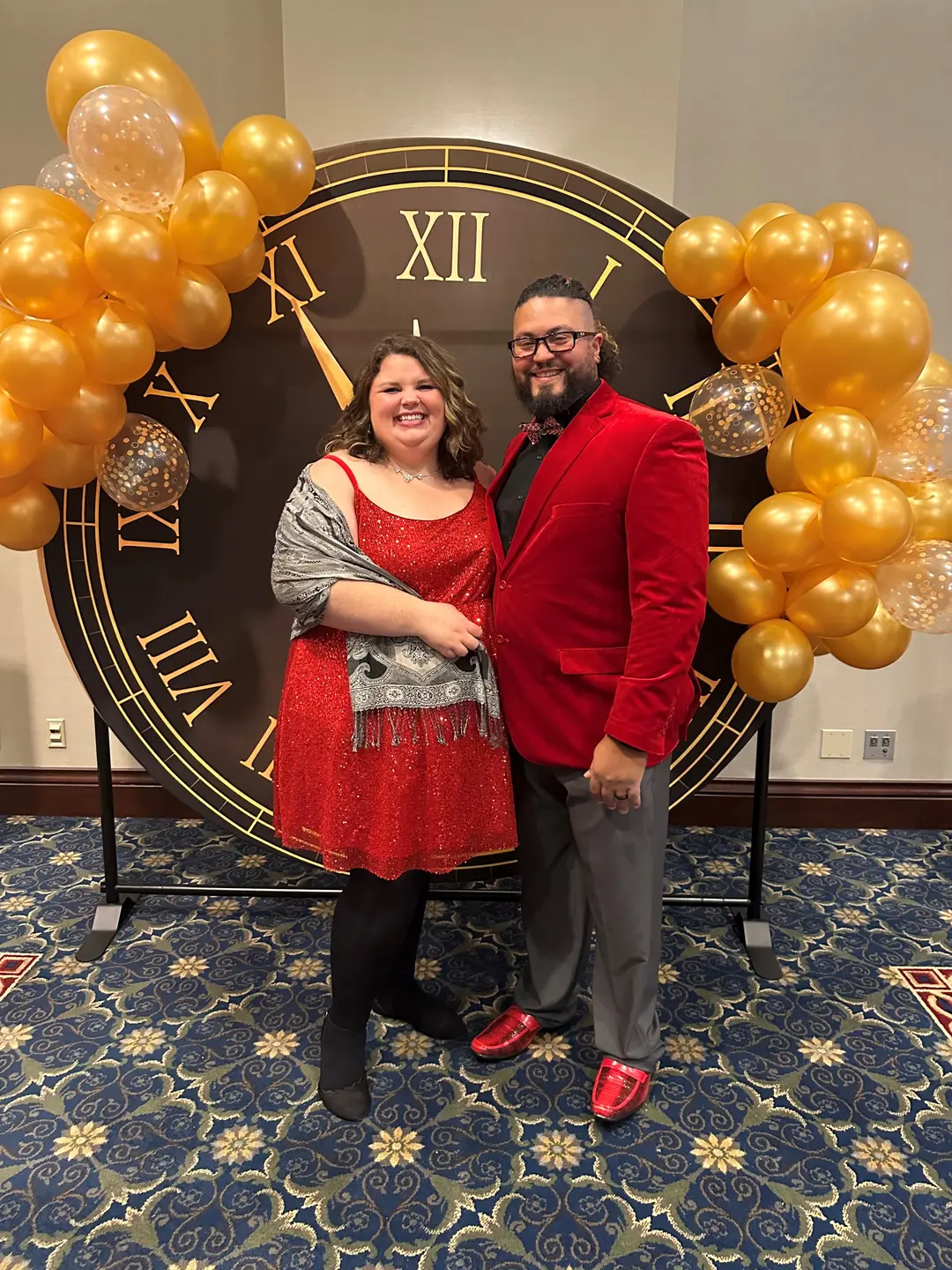 Amanda and Nick Taylor wearing red and posing by black and gold clock and balloons prior to Amanda’s gastric bypass surgery